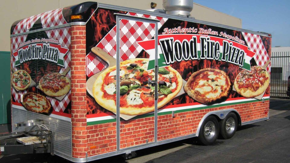 Colorful 20 foot trailer wrap designed and installed for Wood Fire Pizza with large images of pizzas with italian themed background imagery