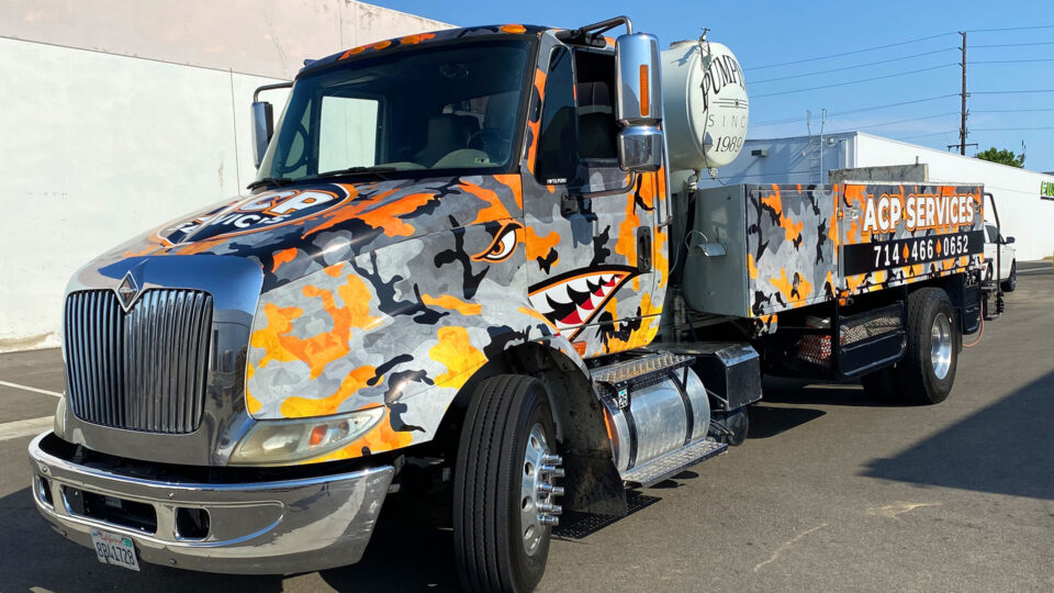 Concrete Truck partial wrap with orange, gray and black camoflauge print and face with mouth and teeth on door