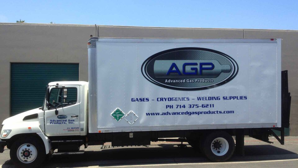 Gray toned round logo partial wrap in center of box truck with contact info for AGP