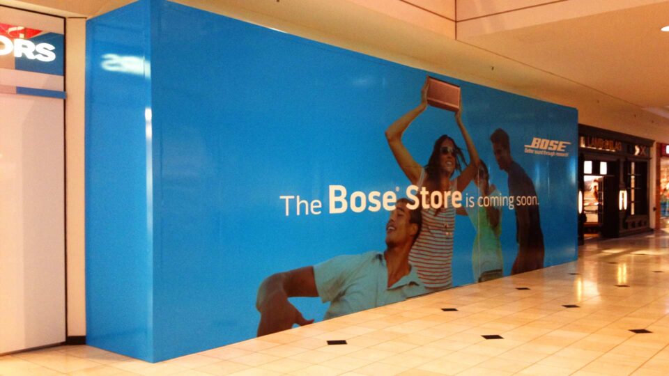 Blue barricade wrap with people holding speaker for Bose Audio