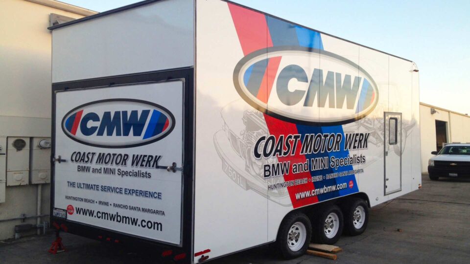 Full Toy hauler wrap featuring red white and blue logo with a BMW in the background for Coast Motor Werk