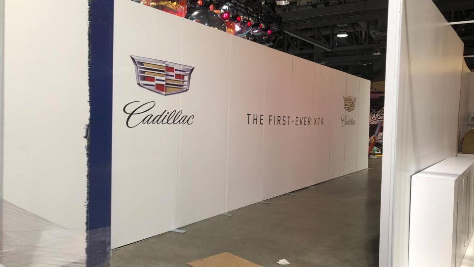 White trade show booth wall with Blue stripe and Cadillac Log