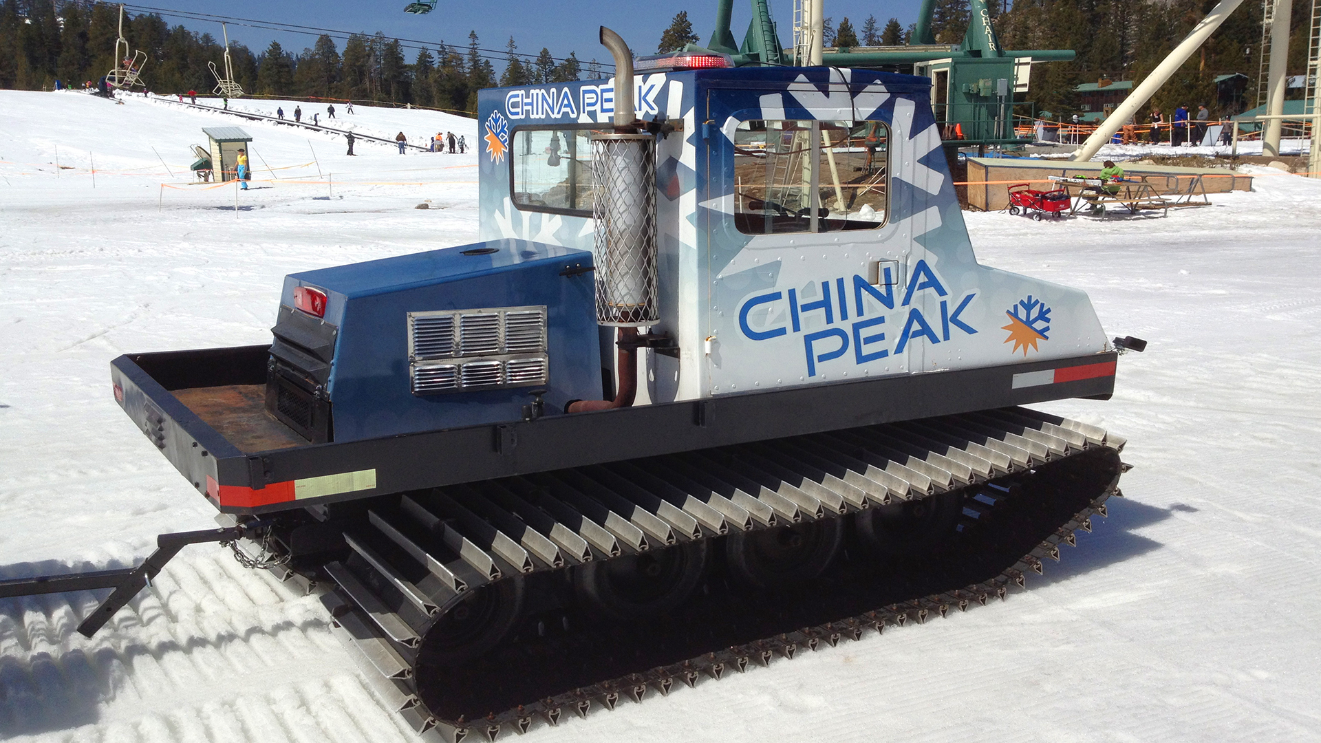 Snow groomer vinyl wrap that says CHINA Peak with logos in blue, white and yellow, parked in snow at ski resort