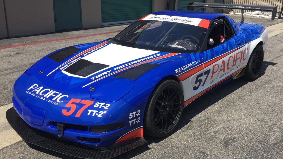 Red, white and blue Corvette race car wrap that says 57 Pacific, sitting in parking lot