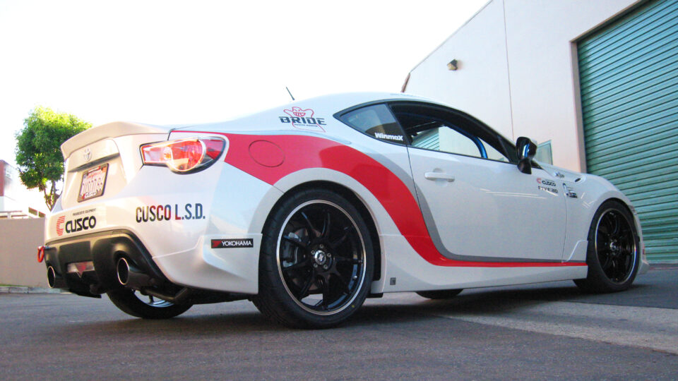 White race car wrap with red and gray stripes and Cusco logo