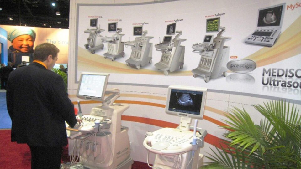 White trade show booth wall graphic with various ultrasound machines displayed