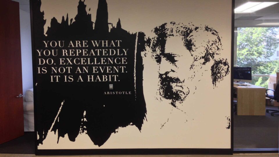Black and white office wall graphic with Aristotle's face and quote