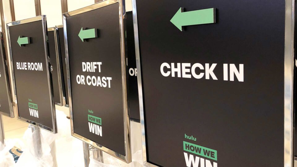 Hotel event directional signs with black background, green arrows and white text