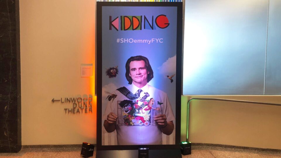 Backlit display panel showing actor with characters from KIDDING tv show
