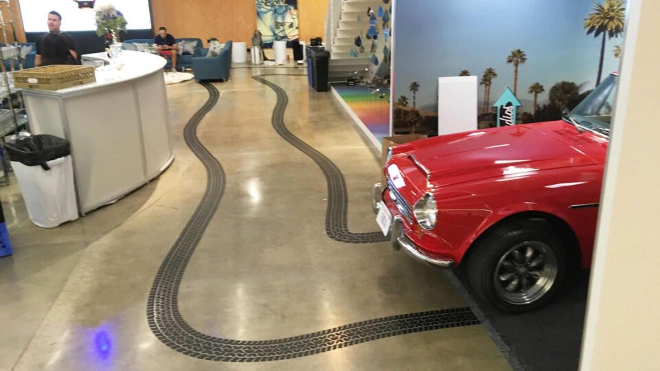 red car in office with black tire track vinyl floor decal on concrete