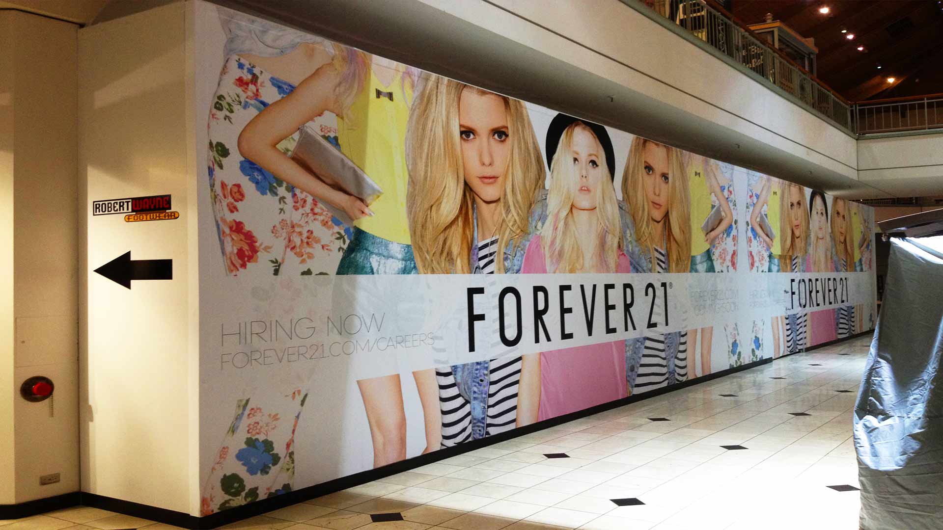 Mall barricade graphic for Forever 21 with models in bright and striped clothing.