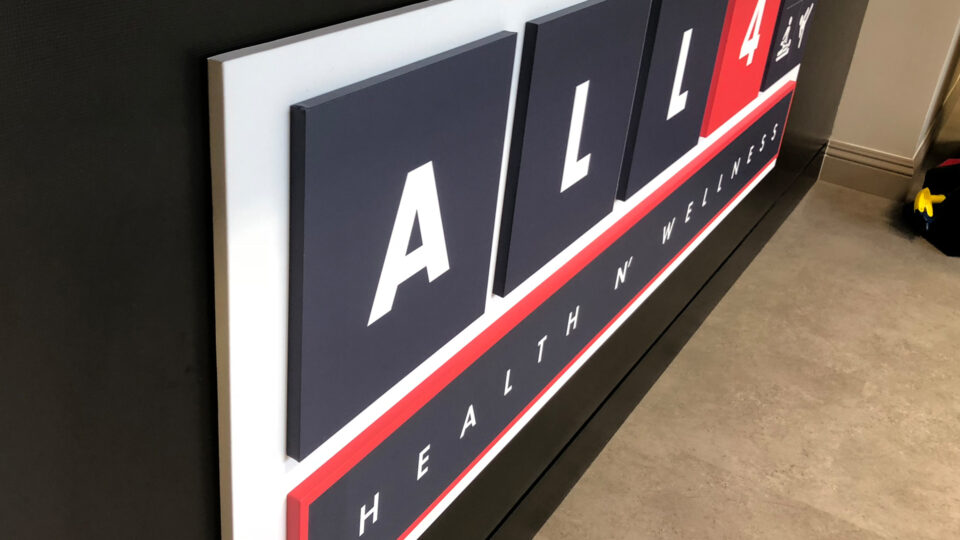 Reception desk sign with white backround with Raised squares that say ALL 4 Health and wellness