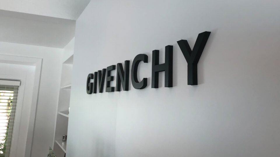 White wall with black router cut sign that says GIVENCHY