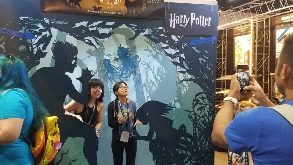 Router Die cut gatorboard display with scene from Harry Potter and 2 show attendees posing for photo
