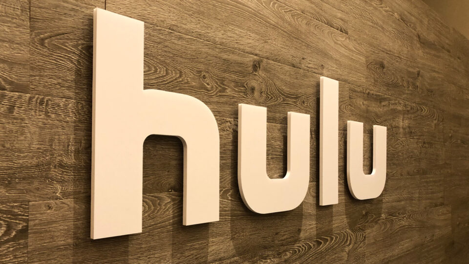 Wood wall with white router cut sign that says HULU