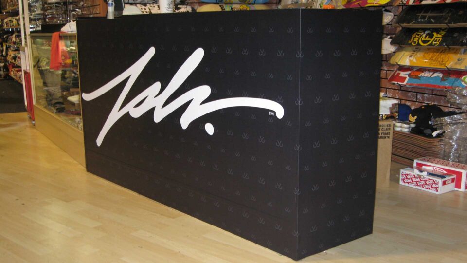 Black vinyl wrap of retail counter with JSLV Logo in white