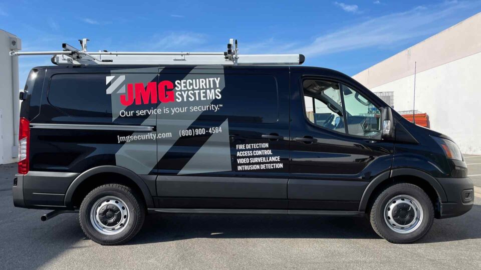 Black Transit partial van wrap with red and white JMG logo and gray stripes