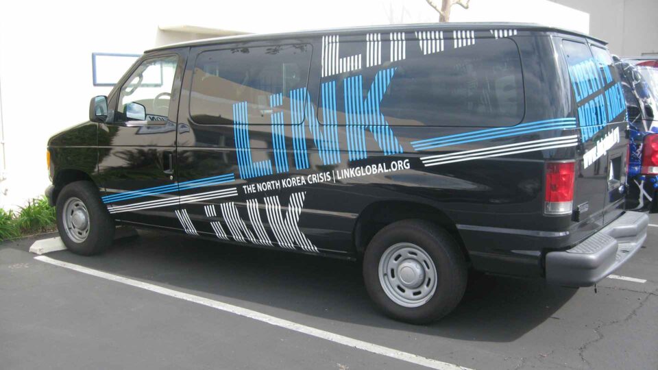 Black Ford Van with blue and white LINK logos partial wrap