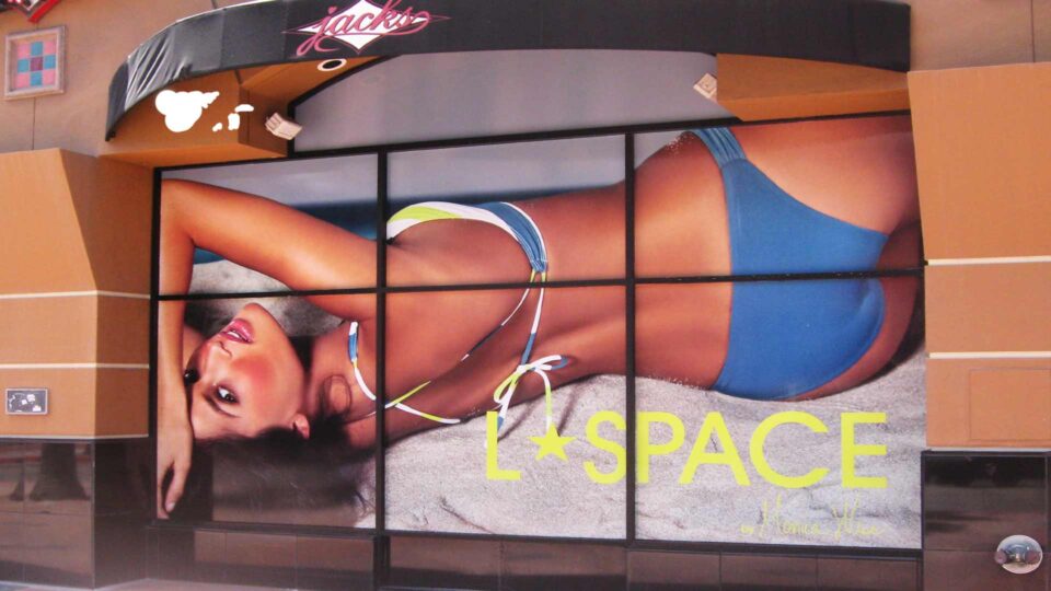 Large solid window graphic of girl looking over shoulder in bikini on beach with Lspace logo in white