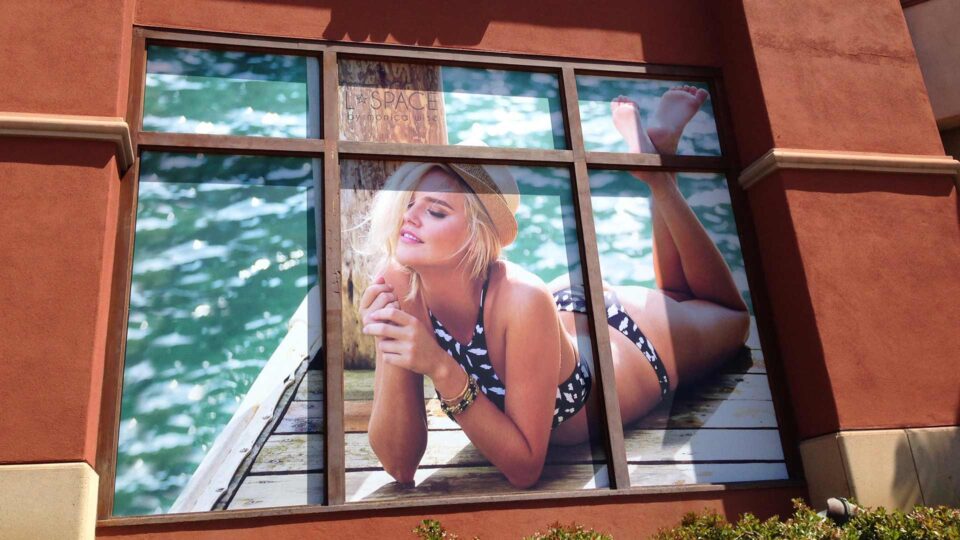 Solid window graphic of girl in bikini on dock with water for L Space Swim.