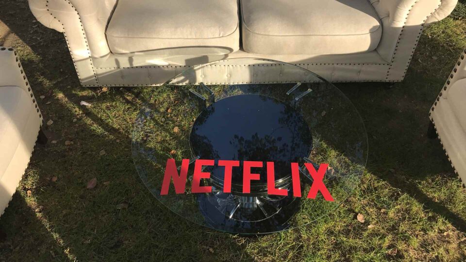 Glass table with red Netflix logo and white couches at special event