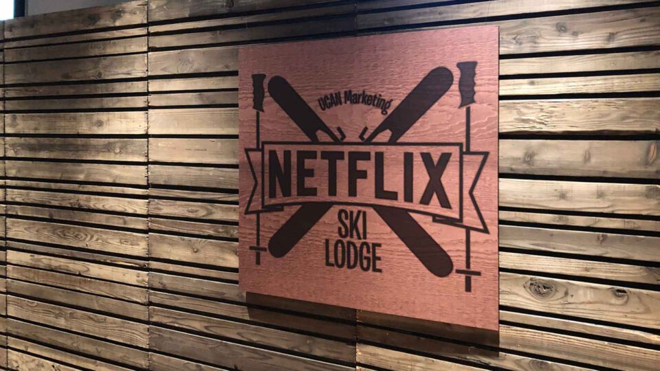 Gatorboard faux wood sign with black Netflx ski lodge logo on wood wall for special event