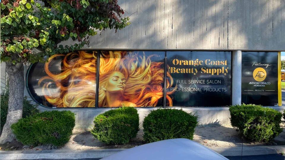 Perforated window graphics featuring a girl with wild hair in orange tones for OC Beauty Supply