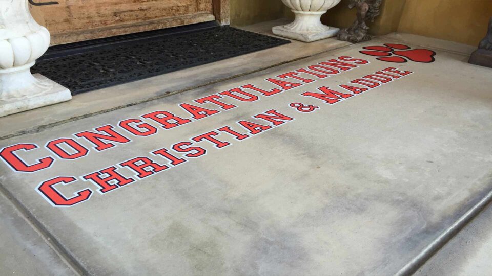 Red, black and white removeable floor decals that say Congratulations Christian & Maddie with a paw print