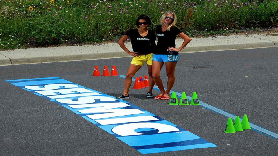 Blue strip concrete floor decal with SEISMIC in white lettering with 2 runners posing at finish line