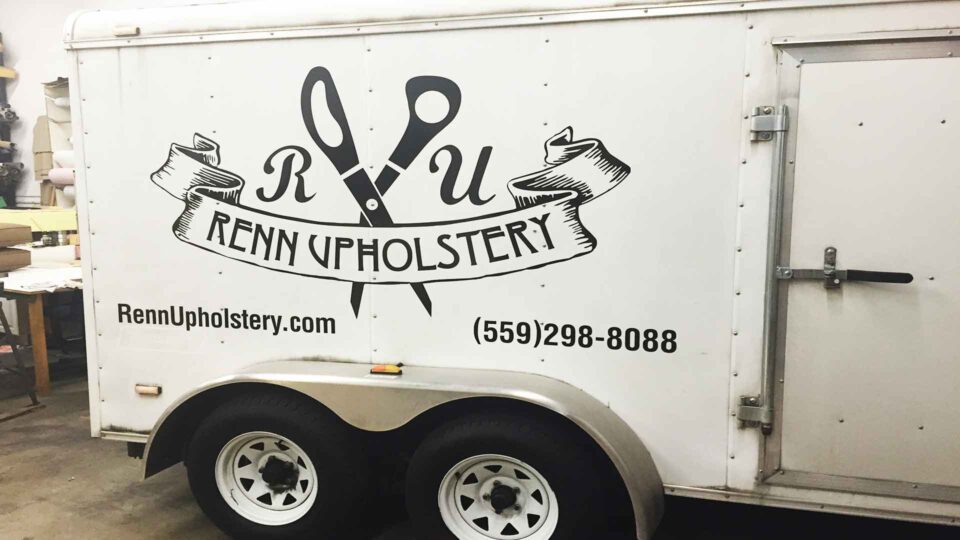 White trailer with black Renn Upholstery logo and scissor partial wrap