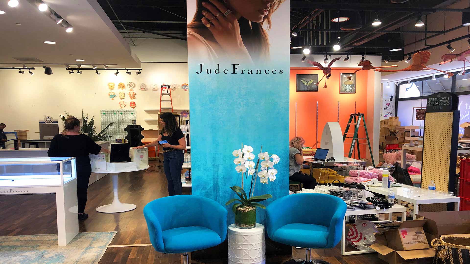 Blue banner with model wearing jewelry inside store with blue chairs and table with orchid