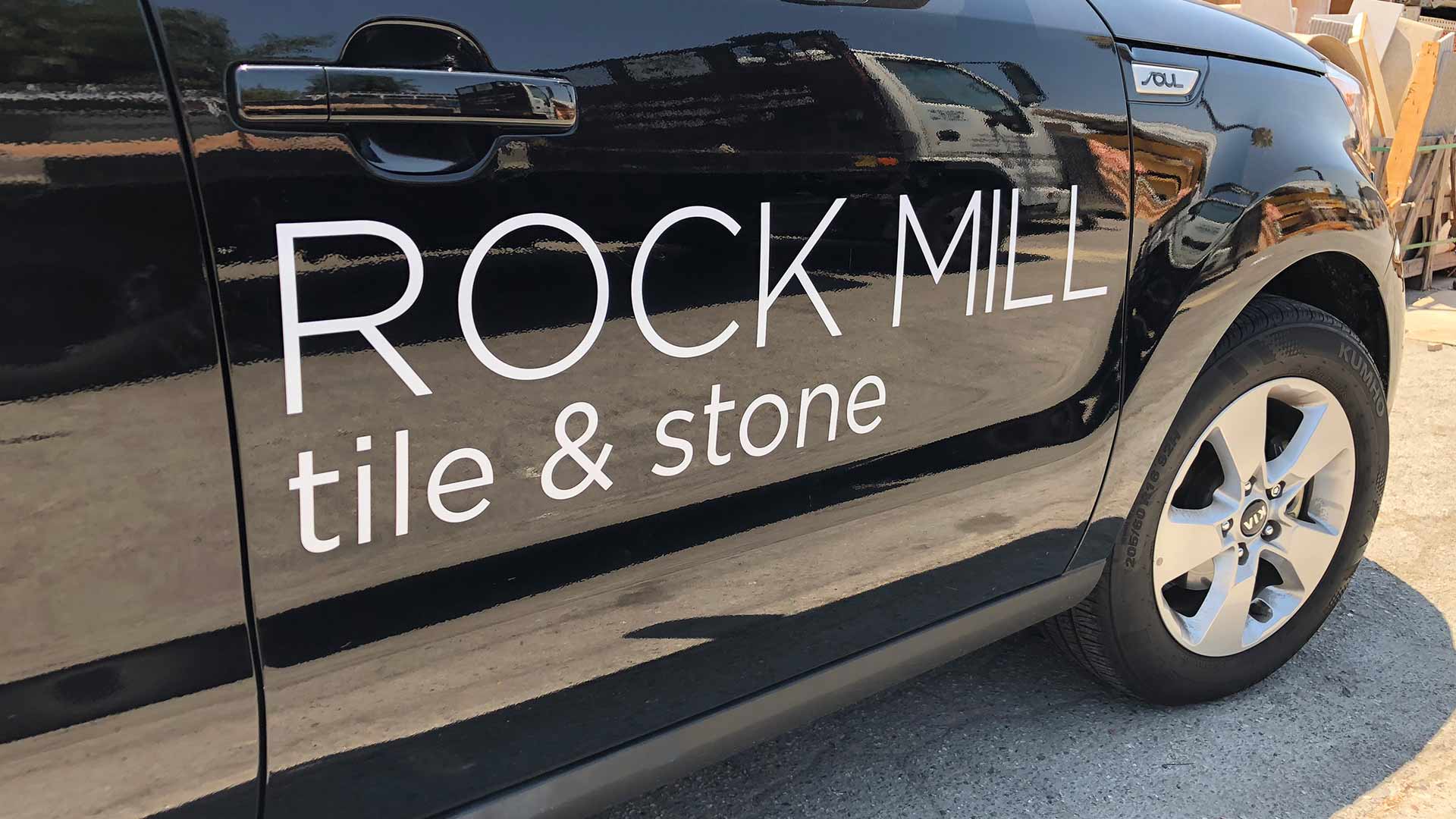 Black door with white die cut decals that say Rock Mill tile & stone