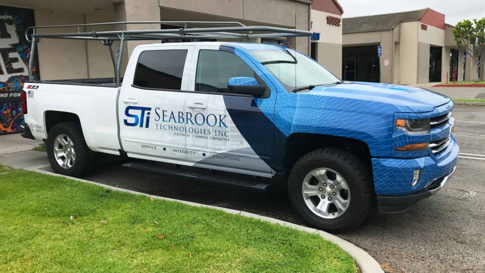 White Chevy Silverado partial truck wrap with blue web design and Seabrook Technologies logos