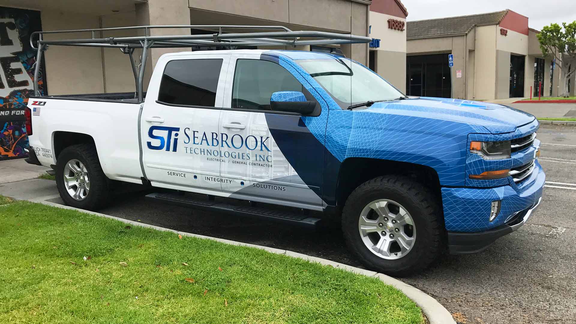 White Chevy Silverado partial truck wrap with blue web design and Seabrook Technologies logos