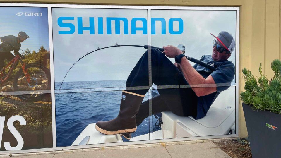 Solid window graphic of man fishing with curved fishing pole in the ocean