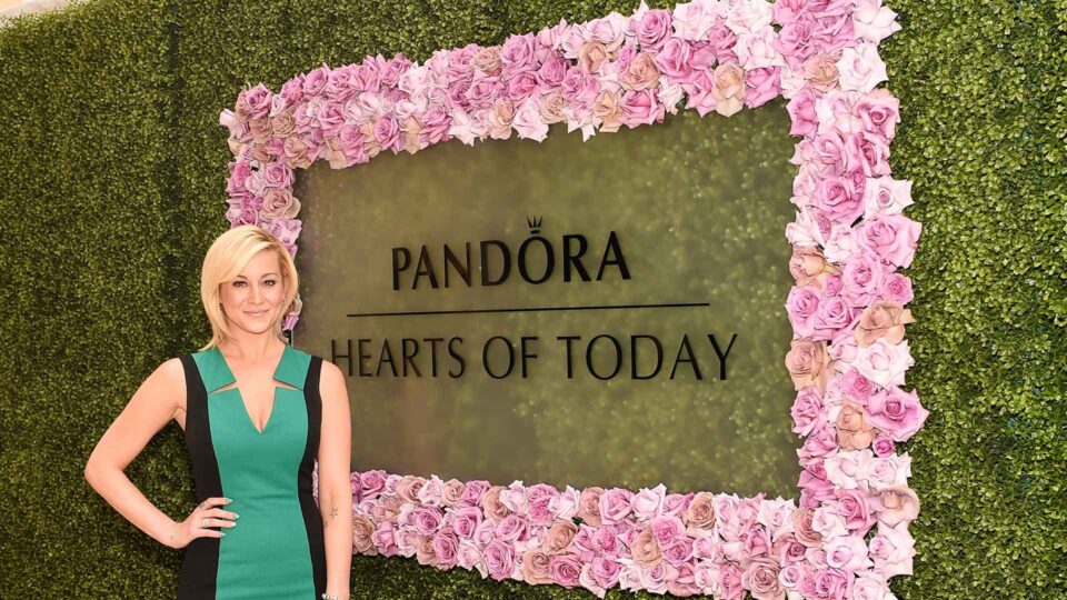 Greenery media wall with pink rose rectangel and Pandora die cut decals on acrylic for special event. Blond female model posing in front.