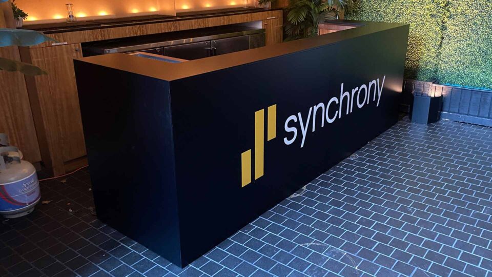 Black bar wrap with white Synchrony logo on black brick floor for special event