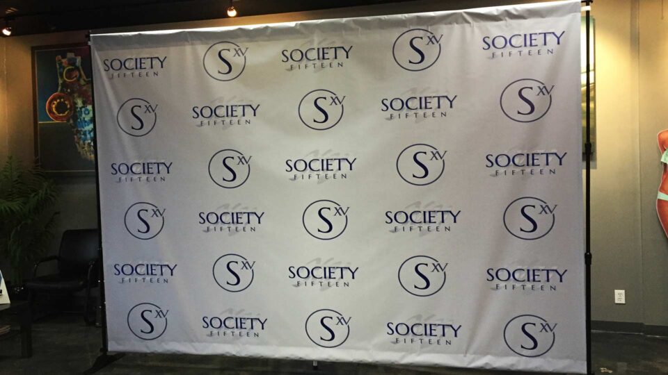 White temporary step & repeat banner with blue logos for special event