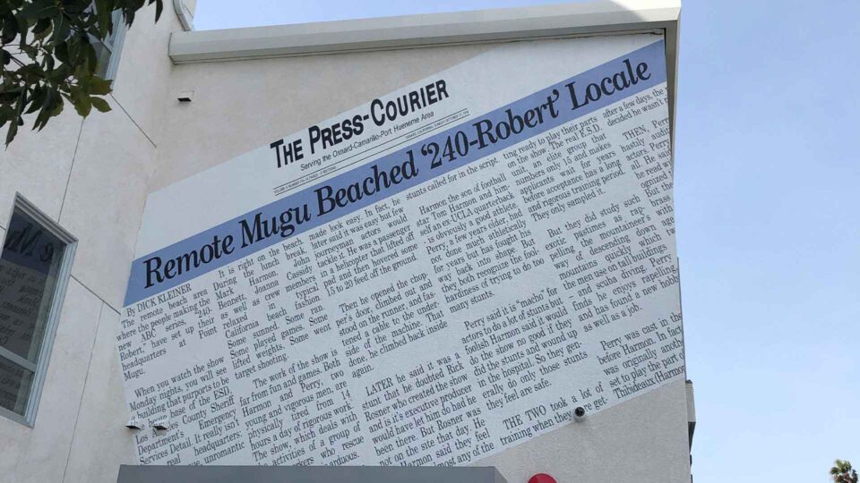 Outside stucco wall mural showing The Press Courier newspaper print