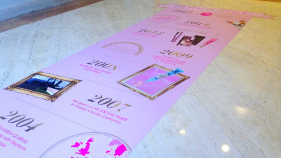 Pink rectangle removeable floor graphic featuring images and gold milestone years