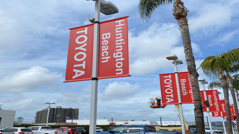2 red banners on the right and left of the top of light pole that says Toyota and Huntington Beach.