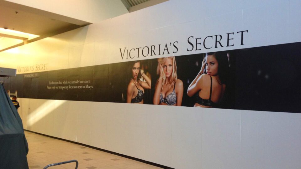 White barricde with 3 models in bras on black stripe in the middle for Victoria's Secret.