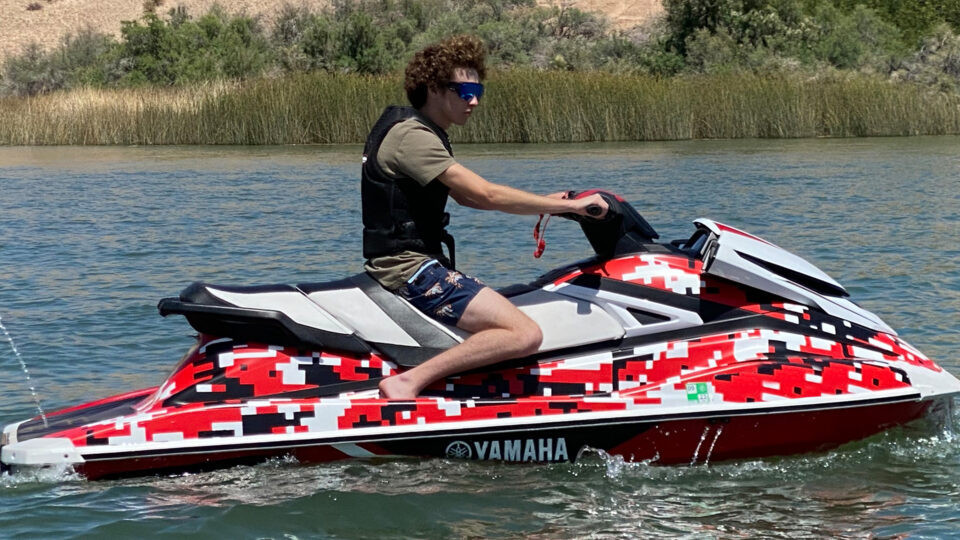 Red, white and black waverunner vinyl wrap with boy driving on lake