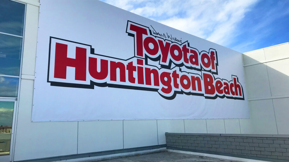 Large white banner on the side of auto dealership that says Toyota of Huntington Beach