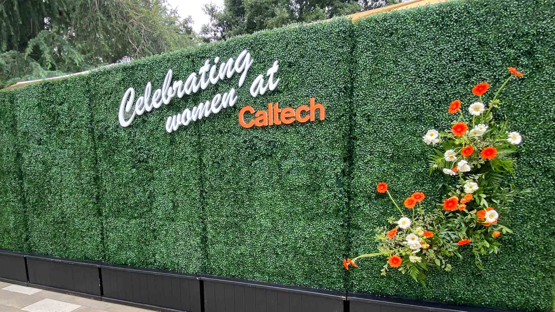 Sign hanging on shrub for Woman's celebration at Caltech