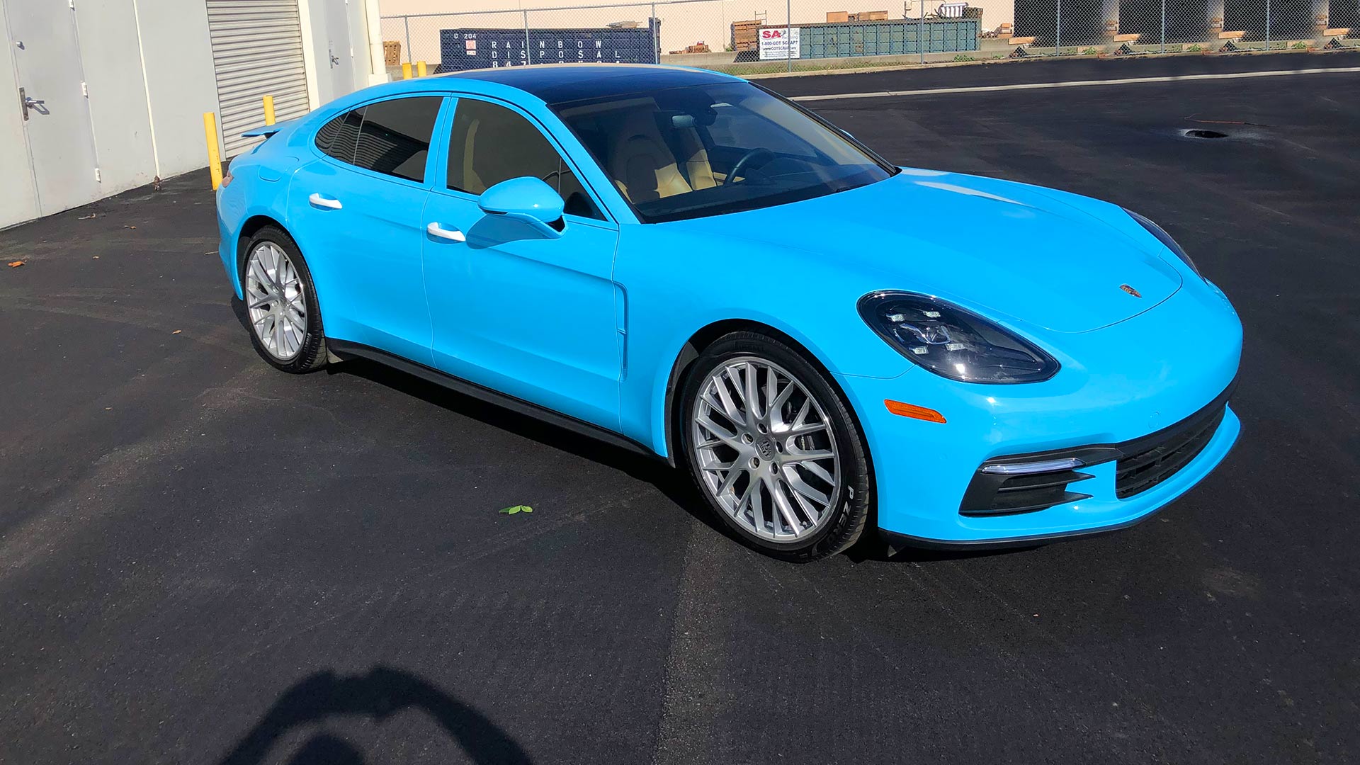 Porsche Panamera color change vehicle wrap that is turquoise blue with black roof and white door handles.