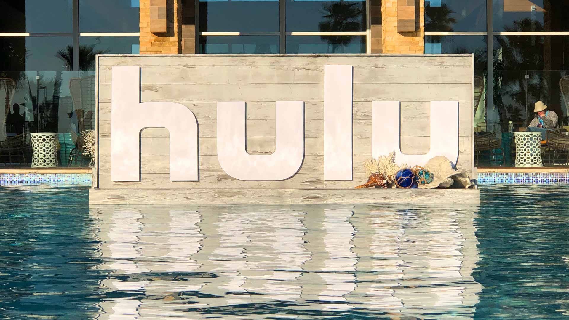 Wood display with White HULU lettering and shells, floating in pool at trade show