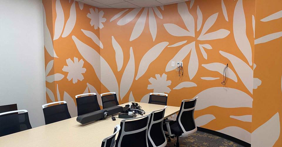 Office with meeting table in front of wall graphic with floral illustration